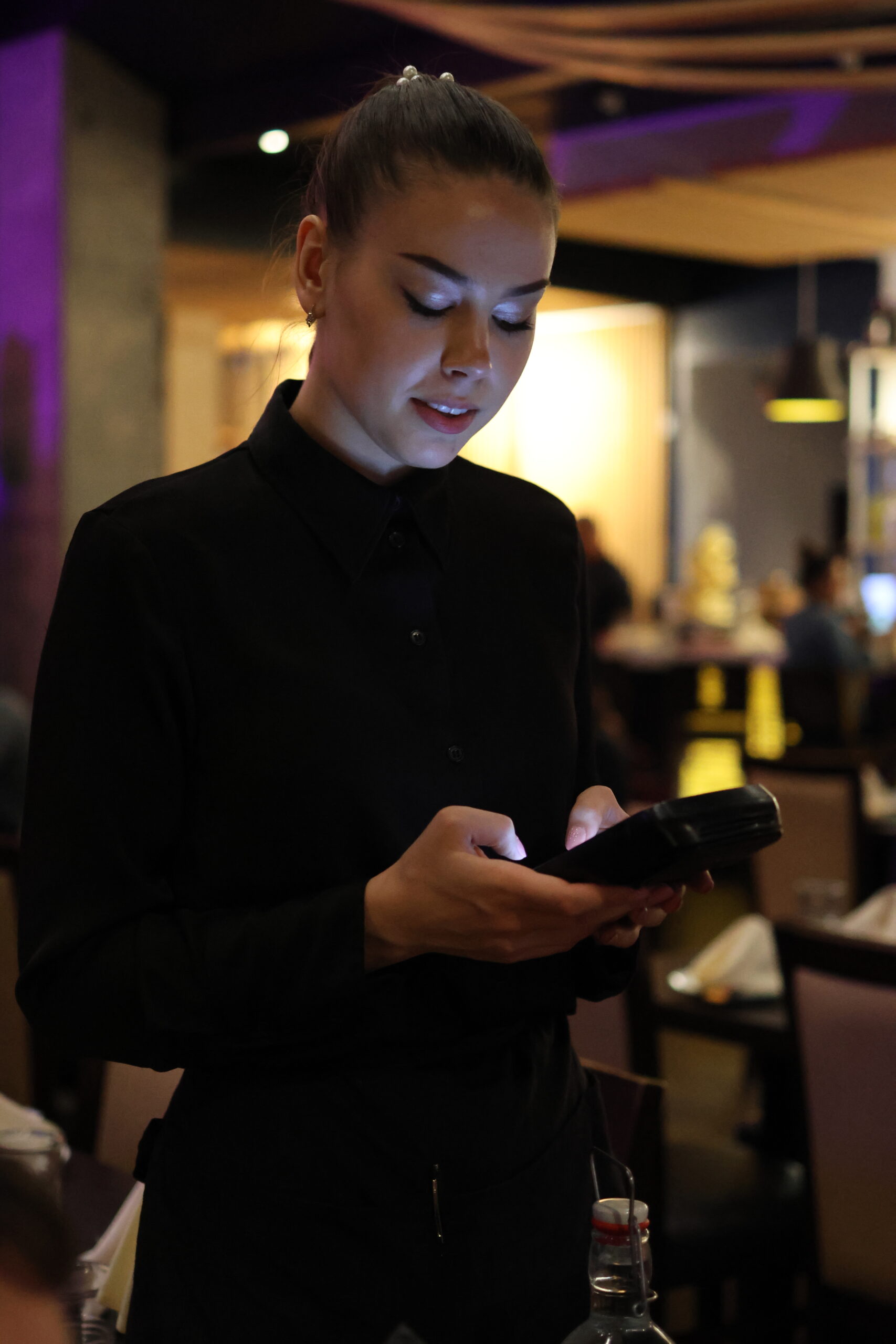 Waitress taking order with handheld device in restaurant