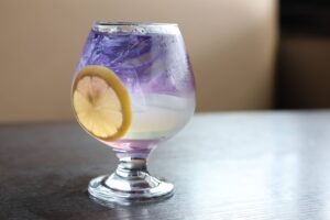 Purple lemonade with lemon slice in glass