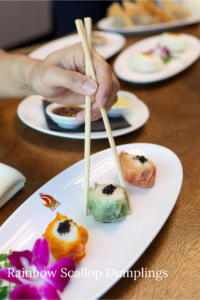 Person picking up colorful dumpling with chopsticks.