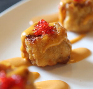 Fried dumpling with spicy sauce and red garnish