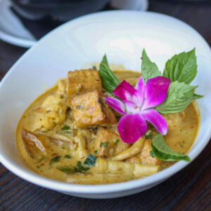 Vegan curry with tofu and colorful flower garnish.