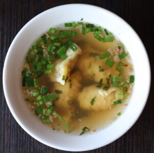 Bowl of wonton soup with green onions.