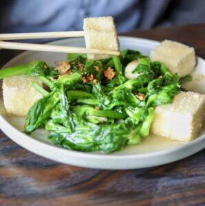 Tofu and greens dish with chopsticks