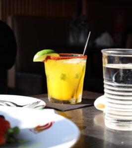 Yellow cocktail with lime and pepper rim.