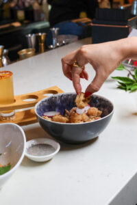 Hand reaching for food in a bowl on counter.