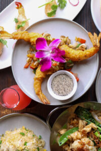 Tempura shrimp with sauce and pink flower garnish.