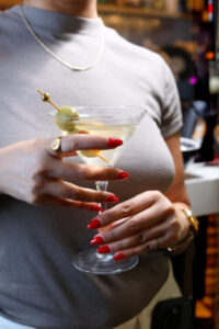 Woman holding a martini with olive garnish.
